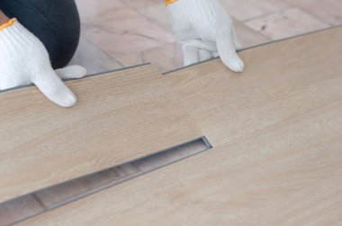 Home renovation with vinyl wood floor Installation for home decoration with laminate vinyl wood floor. Worker installing wood plank for new room. clipart