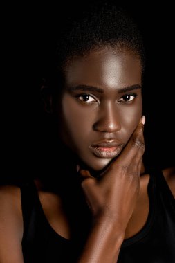Çeneme elini tutarak ve siyahta izole kamera bakıyor güzel Afrikalı-Amerikalı kadın portresi