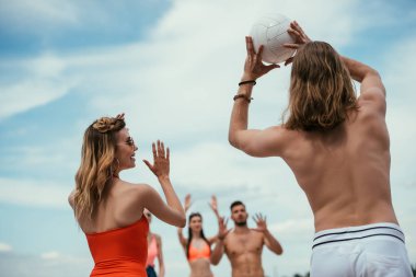 Kumsalda voleybol oynayan genç erkek ve kadın arkadaşlar düşük açılı görünüş