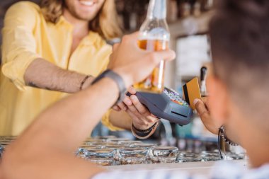 Genç adam bira şişesi holding ve sahil bar, kredi kartı ile ödeme atış kırpılmış