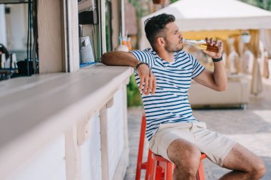 plaj barda otururken cam şişe içki bira genç adam 