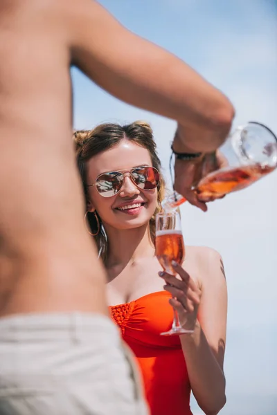 Обрезанный Снимок Мужчины Наливающего Шампанское Улыбающейся Девушке Купальнике — Бесплатное стоковое фото