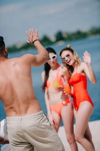 Back View Young Man Ball Waving Hand Smiling Girls Swimwear — Free Stock Photo