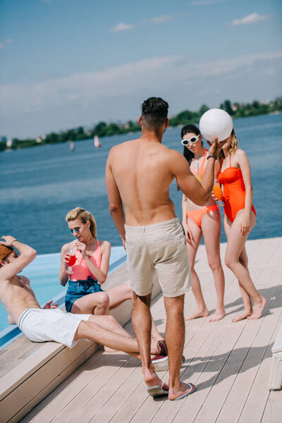 young people spending time with ball and summer cocktails at beach