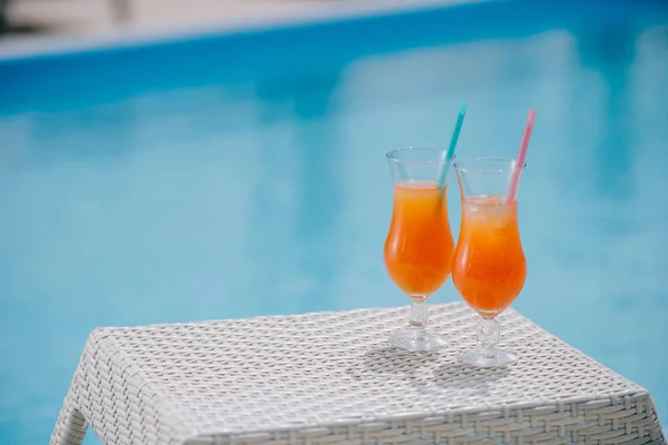 close-up view of summer cocktails with straws at poolside