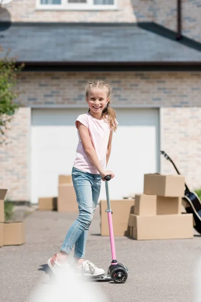 Bambino Felice Cavalcando Scooter Calcio Vicino Scatole Chitarra Acustica Fronte — Foto stock gratuita