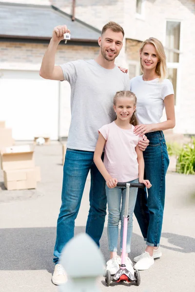 Hombre Sosteniendo Llave Con Baratija Mientras Esposa Abrazando Hija Patinete — Foto de Stock