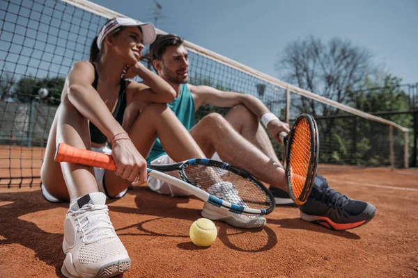 Net Üzerinden Eğilerek Tenis Kortunda Rahatlatıcı Genç Çift — Stok fotoğraf