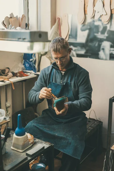 成熟的鞋匠持有引导工件 并在他的传统车间坐在鞋底工作 — 图库照片
