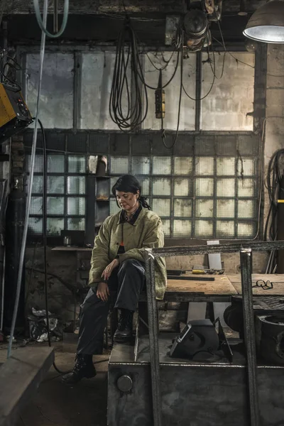 Soldador Feminino Cansado Sentado Mesa Enquanto Descansa Durante Trabalho — Fotografia de Stock