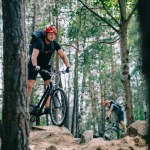 Extreme young trial bikers riding at beautiful pine forest