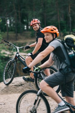 mutlu genç deneme bisikletçileri üzerinde kayalık uçurum arka plan üzerinde bulanık çam ormanı ile ayakta