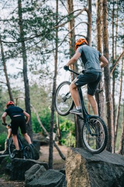 atletik genç deneme bisikletçileri kayalar üzerinde stunts gerçekleştirmek