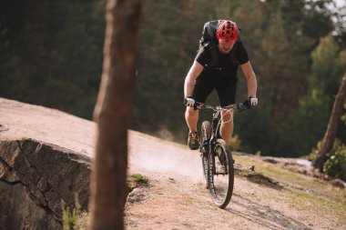 trial biker riding on rocky clifff outdoors clipart