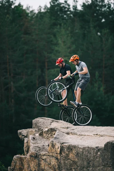 Risky Trial Bikers Standing Back Wheels Rocky Cliff Blurred Pine — Stock Photo, Image