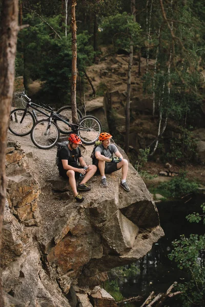 高角度观看快乐的年轻试验骑自行车放松在岩石悬崖骑后 — 图库照片