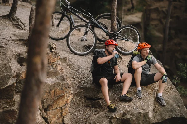 若いトライアル自転車乗車後岩の崖にリラックスして食事のハイアングル — ストック写真