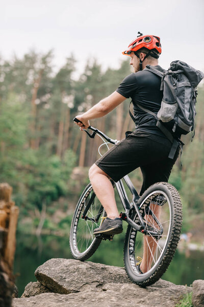 trial biker standing with bicycle on rock outdoors