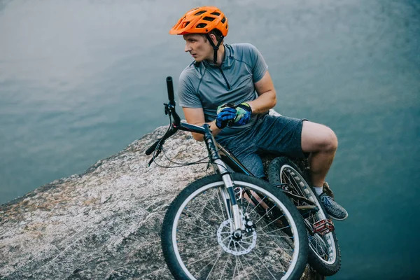 Young Trial Biker Relaxing Rocky Cliff Water Looking Away — Stock Photo, Image