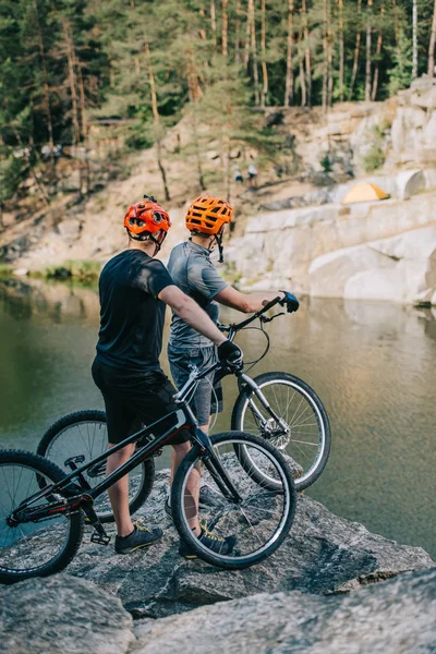 Jóvenes Ciclistas Trial Activos Pie Acantilado Rocoso Frente Lago Montaña — Foto de stock gratis