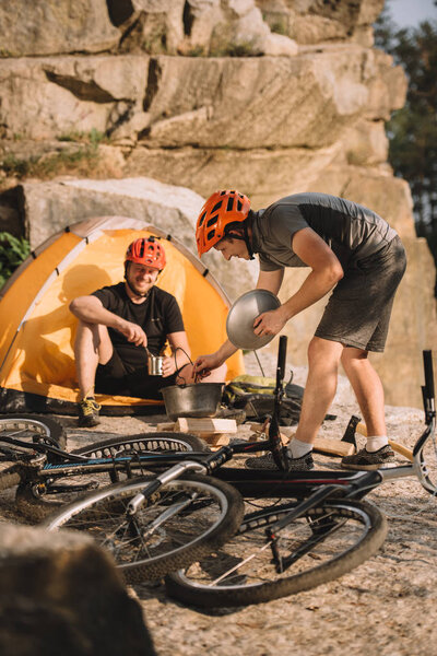 young trial bikers cooking food on camping outdoors