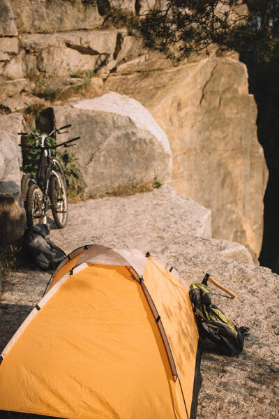 camping tent with trial bikes and backpack on rocky cliff