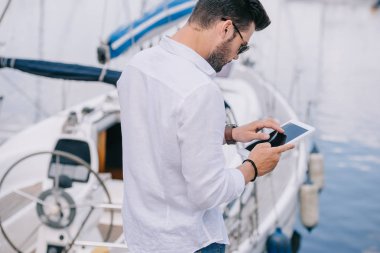 arkadan görünüşü yat dijital tablet kullanarak güneş gözlüklü adam