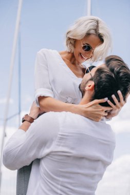 sarılma ve birbirlerine yatta gülümseyen güneş gözlüğü mutlu genç çiftin düşük açılı görünüş