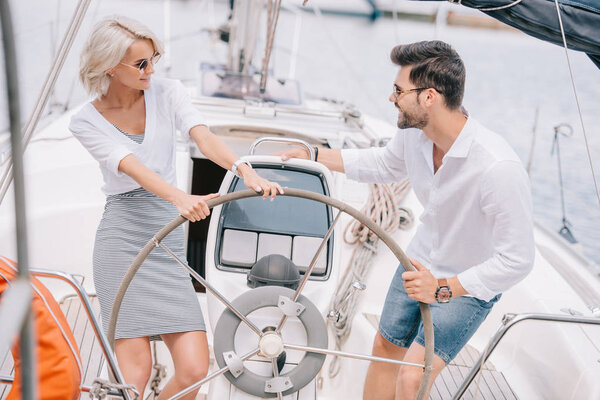 high angle view of happy young couple in sunglasses smiling each other on yacht