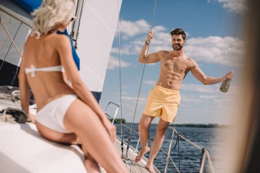 handsome shirtless man with bottle of champagne and his girlfriend on yacht  clipart