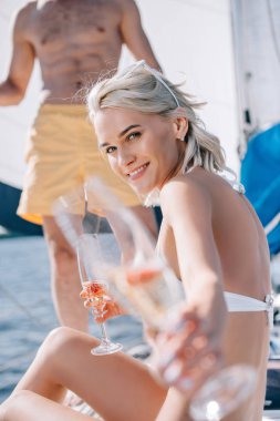 cropped image of man and his smiling girlfriend showing glass of champagne on yacht  clipart