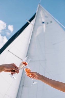 cropped image of boyfriend and girlfriend clinking by glasses with champagne on yacht  clipart