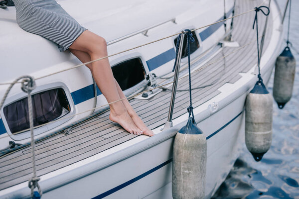 обрезанный снимок молодой босиком женщины, сидящей на яхте
