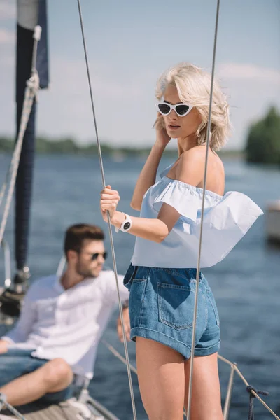Mooie Jonge Vrouw Zonnebril Permanent Jacht Terwijl Man Zit Achter — Stockfoto
