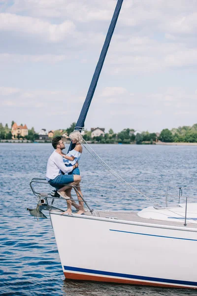 美丽快乐的年轻夫妇坐在游艇上的侧面视图和拥抱 — 图库照片