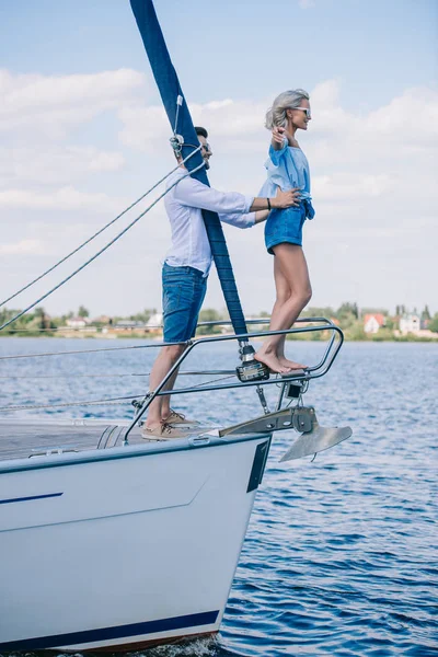 サングラスのヨットの上で一緒に時間を過ごす幸せな若いカップルの側面図 — ストック写真