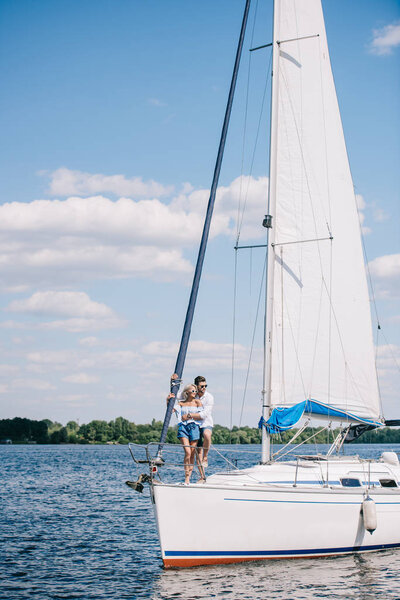 beautiful young couple hugging while spending time together on yacht