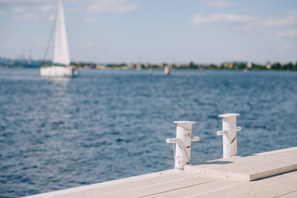 пустой деревянный пирс и яхта на заднем плане в летний день
