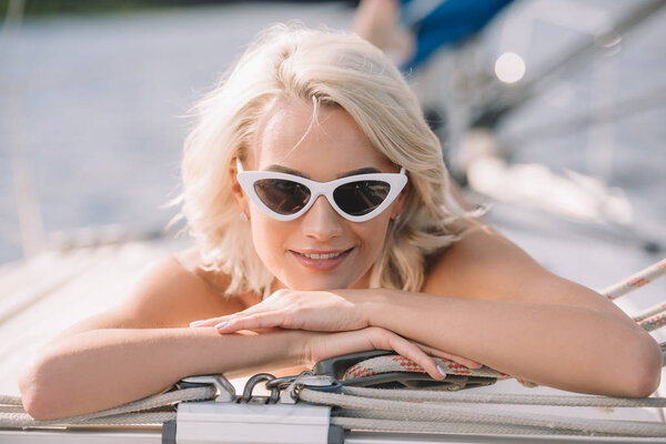 selective focus of attractive young woman in sunglasses laying on yacht 