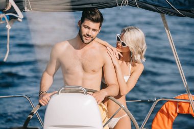 genç çekici kadın kucaklayan gömleksiz erkek o yat direksiyon süre