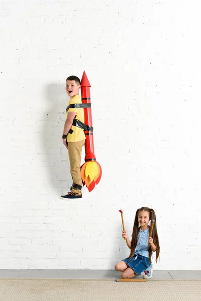 妹妹假装在火玩具火箭与兄弟在家里 — 图库照片
