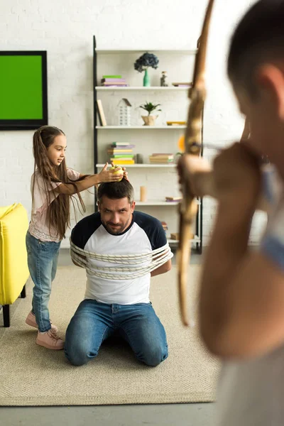 Niños Desobedientes Jugando Con Padre Atado Fingiendo Disparar Con Arco — Foto de Stock