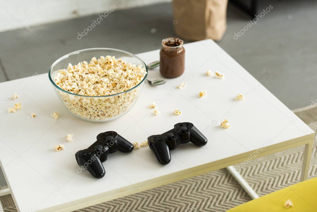 glass bowl with popcorn and joysticks on table in living room
