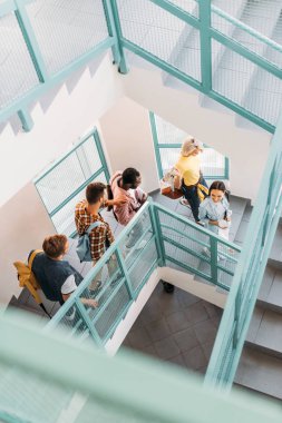 high angle view of group of young students walking down stairs at college clipart