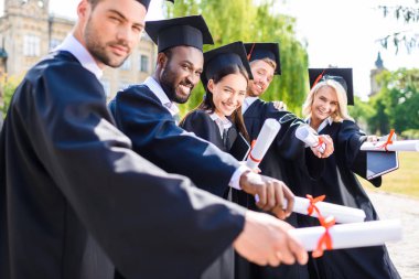 tutan genç mezun öğrencilerin diploma haddelenmiş