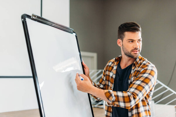 Красивая молодая учительница указывает на чистую доску
