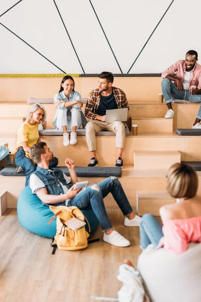 çok ırklı genç öğrenciler zaman birlikte üniversitede ahşap tribünlerin üzerinde harcama.