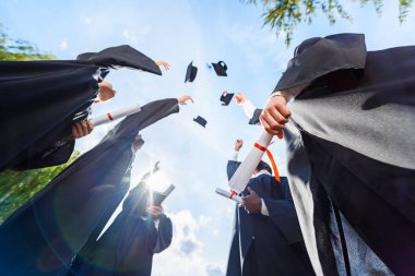 mezun öğrencilerin mavi gökyüzü önünde şapka atma alttan görünüm