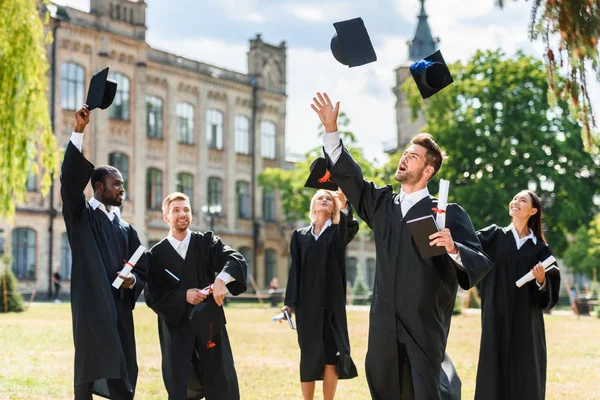 Młody Szczęśliwy Absolwentów Rzucanie Się Graduation Czapki Ogrodzie Uniwersytetu — Zdjęcie stockowe