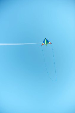 colorful kite flying high in blue clear sky clipart